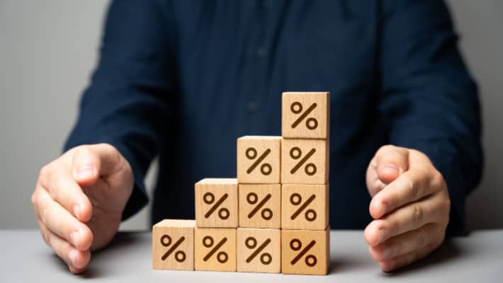 Person with wooden blocks showing percentage symbols stacked in steps