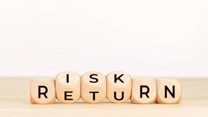 wooden blocks arranged to spell out risk and return terms on a table.