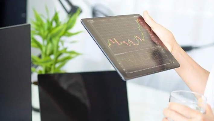 Woman holds tablet checking the trading charts