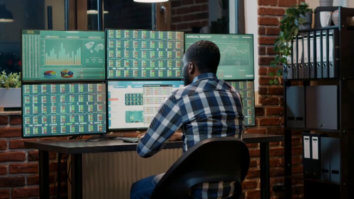 A man monitoring various screens showing financial trading information