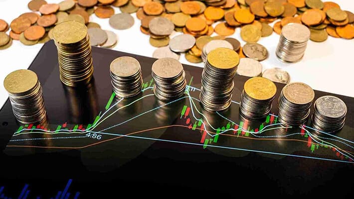 coins are arranged on the tablet displaying candlestick charts