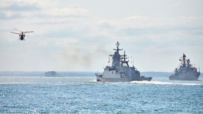 Two naval vessels and a helicopter over the ocean