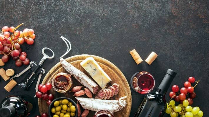 A spread of gourmet snacks including cheese, cured meats, olives, and wine