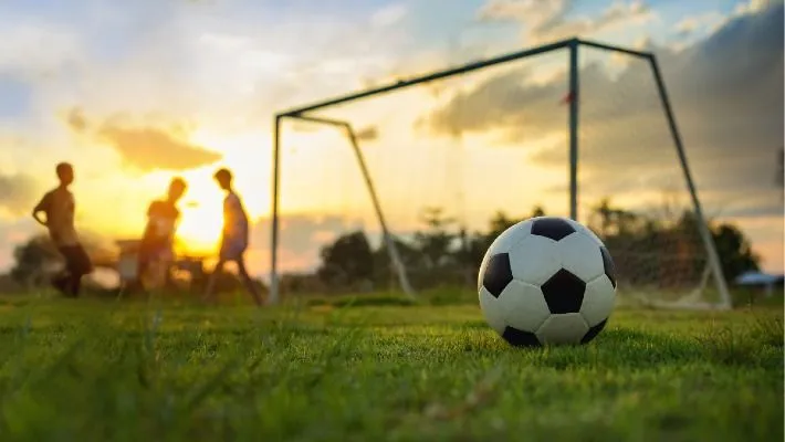 a football ball on the grass with people in the background