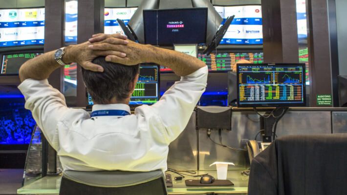 man sitting on a table while trading on his desktop