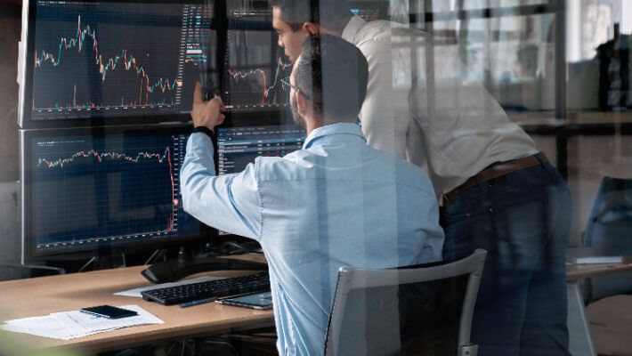 Two men reviewing data on a computer monitor