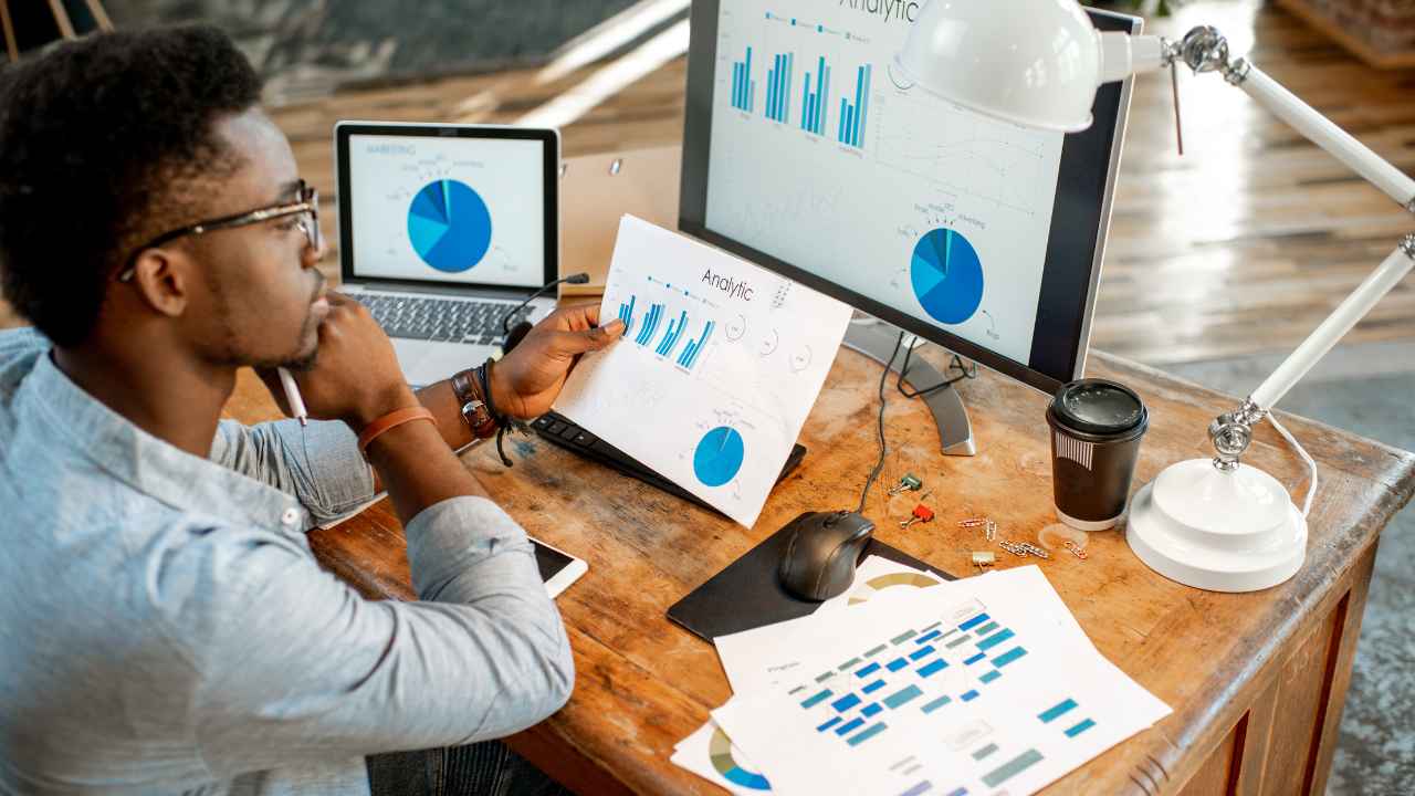 A person sitting at a desk with a computer and a graph