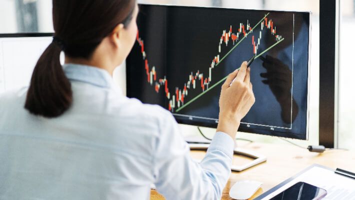 A woman drawing trend lines on a computer screen.