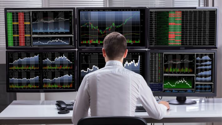 workstation with multiple monitors displaying financial charts